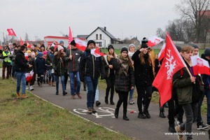Zdjęcie przedstawia maszerujących ludzi z flagami Polski. (photo)