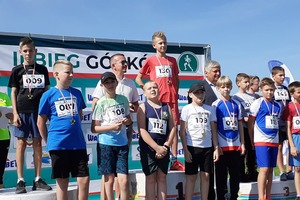 Grupa młodych biegaczy na podium wraz z wręczającymi medale burmistrzem i przedstawicielem sponsorów (photo)