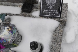 Tabliczka Powstańca Wielkopolskiego, przy której znajduje się zapalony znicz (photo)