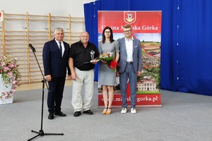 Na zdjęciu znajduje się trzech mężczyzn oraz kobieta trzymająca bukiet kwiatów. (photo)