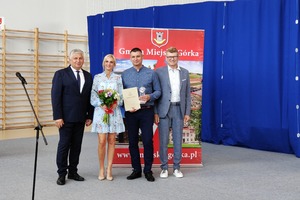 Na zdjęciu znajduje się trzech mężczyzn oraz kobieta trzymająca bukiet kwiatów. (photo)