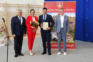 Na zdjęciu znajduje się trzech mężczyzn oraz kobieta trzymająca bukiet kwiatów. (photo)