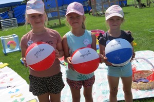 Na zdjęciu znajdują się trzy dziewczynki trzymające piłki plażowe. (photo)