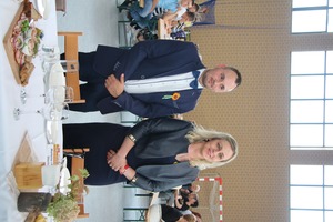 Na zdjęciu znajduje się kobieta i mężczyzna stojący za dożynkowym stołem odbierający wieniec (photo)