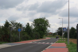 Nowa droga na ul. Podgórnej. Po prawej stronie, wzdłuż drogi obok chodnika stoją lampy, po lewej rosną drzewa. (photo)