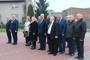 Grupa dorosłych, stojących mężczyzn  i kobiet, obecnych przy uroczystości wciągania flagi na maszt (photo)